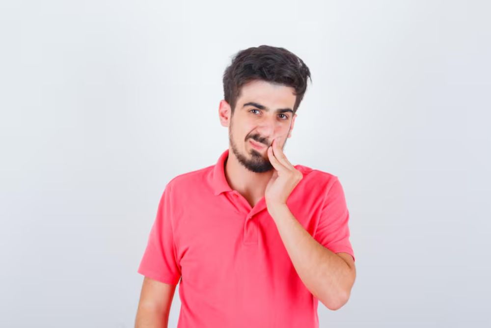 man holding his cheek due to swelling after a tooth extraction procedure
